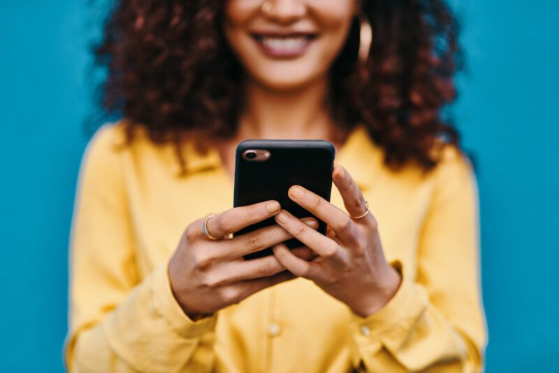 You gotta love social media Cropped shot of an unrecognizable woman smiling while using a smartphone against a blue background
